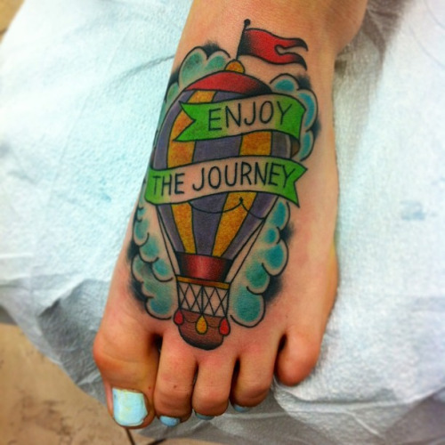Enjoy The Journey Banner And Hot Balloon Tattoo On Left Foot