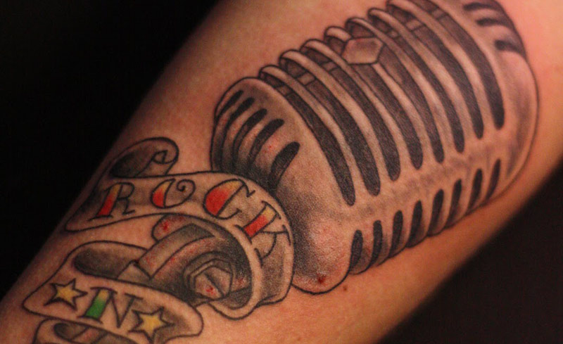 Grey Ink Mic And Rock In Banner Tattoo
