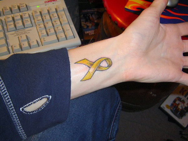 Yellow Ribbon Tattoo On Left Wrist