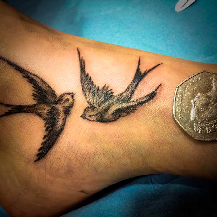 Black And Grey Two Flying Birds Tattoo Design For Foot