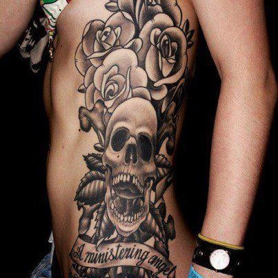 Black Ink Gothic Skull With Roses And Banner Tattoo On Side Rib