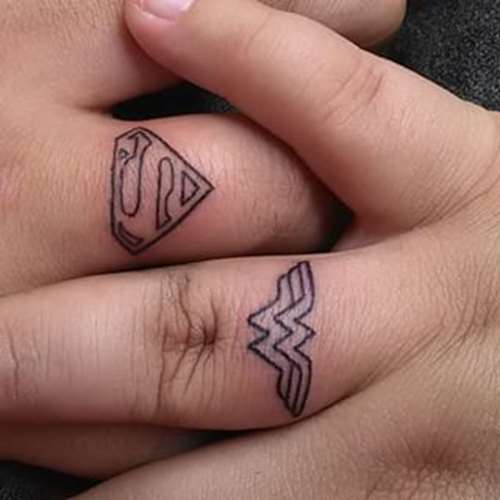 Black Outline Superman And Wonder Women Logo Tattoo On Finger