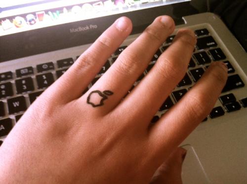 Black Outline Apple Logo Ring Tattoo On Finger