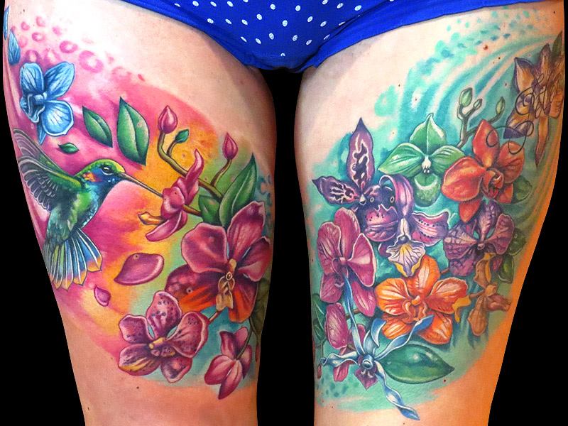 Colorful Flowers And Hummingbird Tattoos On Both Thigh
