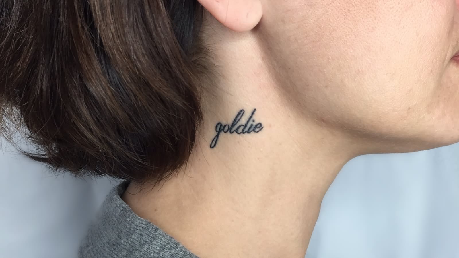 Goldie Lettering Tattoo On Girl Side Neck