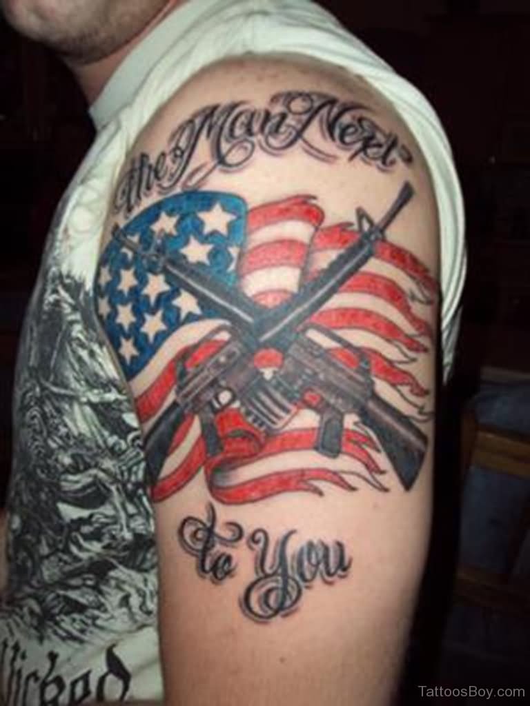 Torn USA Flag With Two Crossing Gun Tattoo On Man Left Shoulder