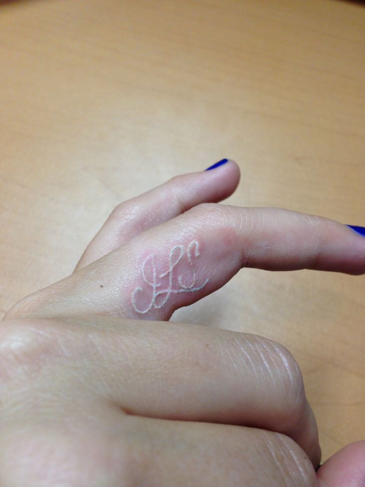 White Ink Lettering Tattoo On Girl Finger