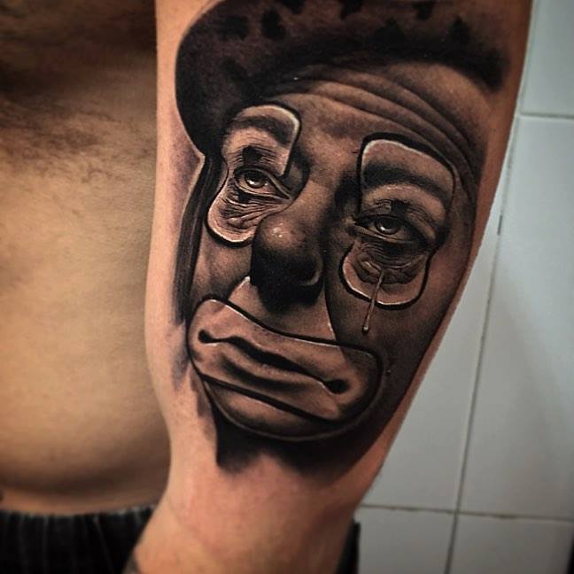 Grey Ink Crying Joker Head Tattoo On Left Bicep by Samu Rich