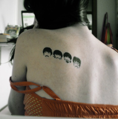 Simple Black Beatles Faces Tattoo On Left Back Shoulder