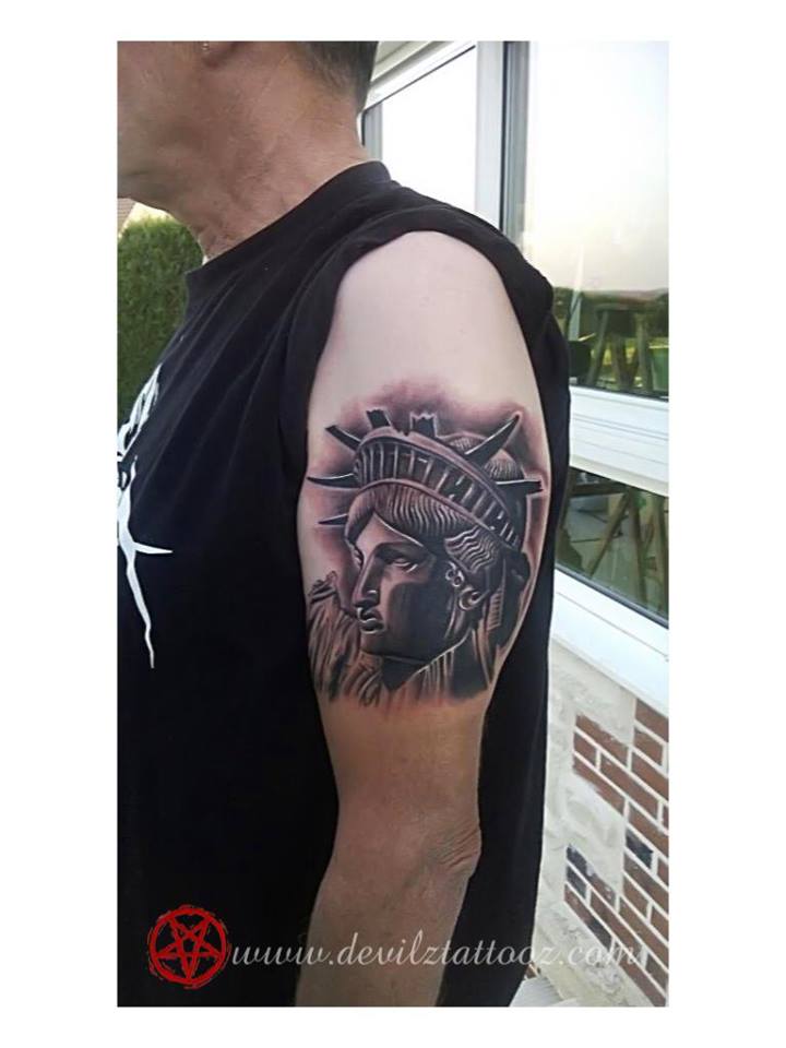 Black Ink Statue Of Liberty Head Tattoo On Left Half Sleeve