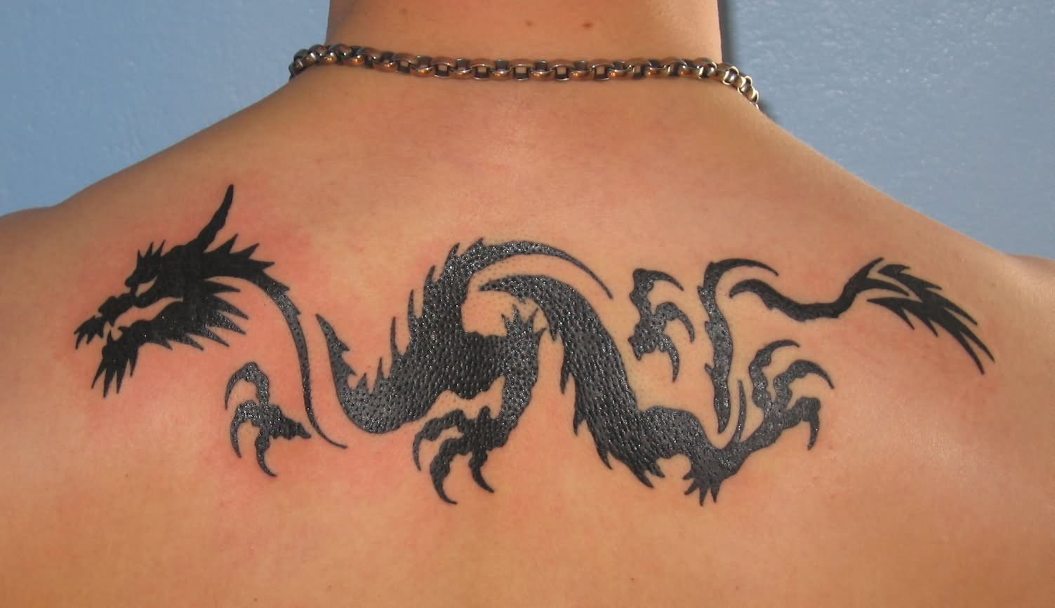 Black Tribal Dragon Tattoo On Man Upper Back