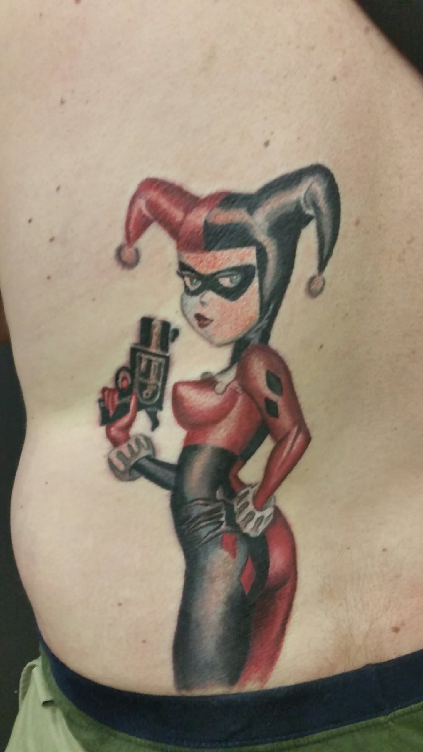 Lower Back Harley Quinn With Gun Tattoo