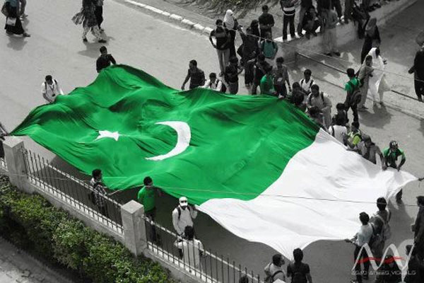 A Group Of Students Walking With Big Size Flag Celebrating Independence Day Of Pakistan