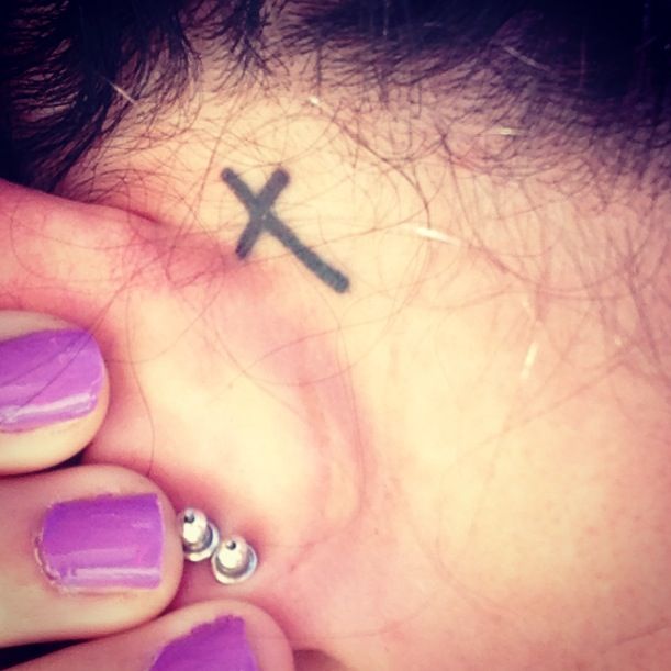 Black Cross Tattoo On Girl Left Behind The Ear