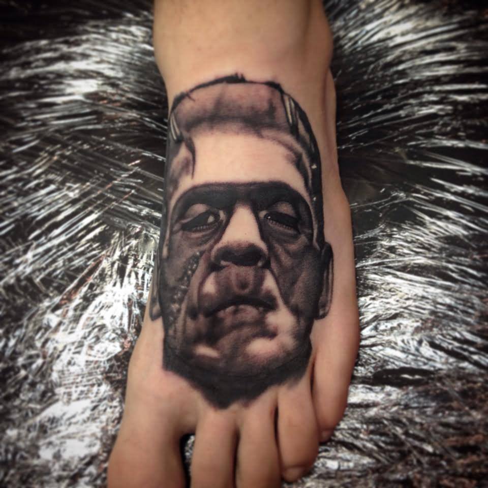 Black Ink 3D Frankenstein Head Tattoo On Left Foot