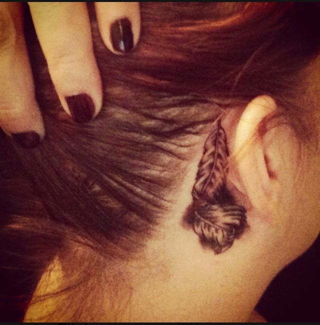 Black Ink Feather Tattoo On Girl Right Behind The Ear