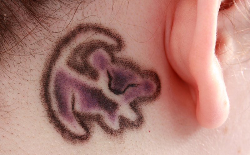 Black Ink Simba Tattoo On Right Behind The Ear