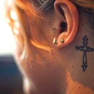 Cool Black Outline Cross Tattoo On Girl Left Behind The Ear