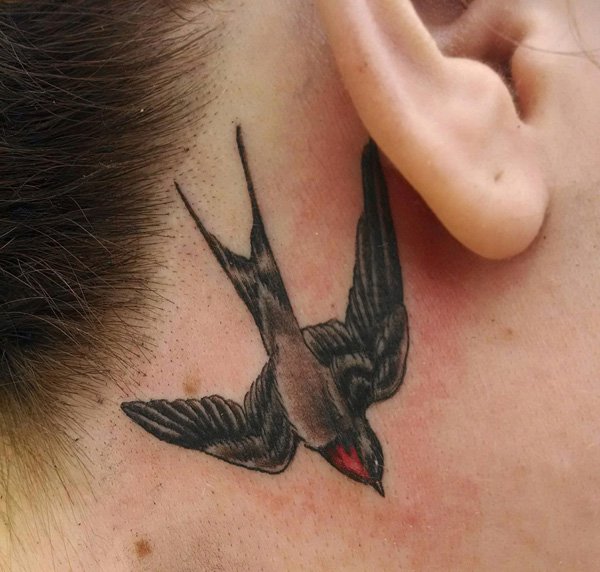 Cool Flying Bird Tattoo On Girl Right Behind The Ear
