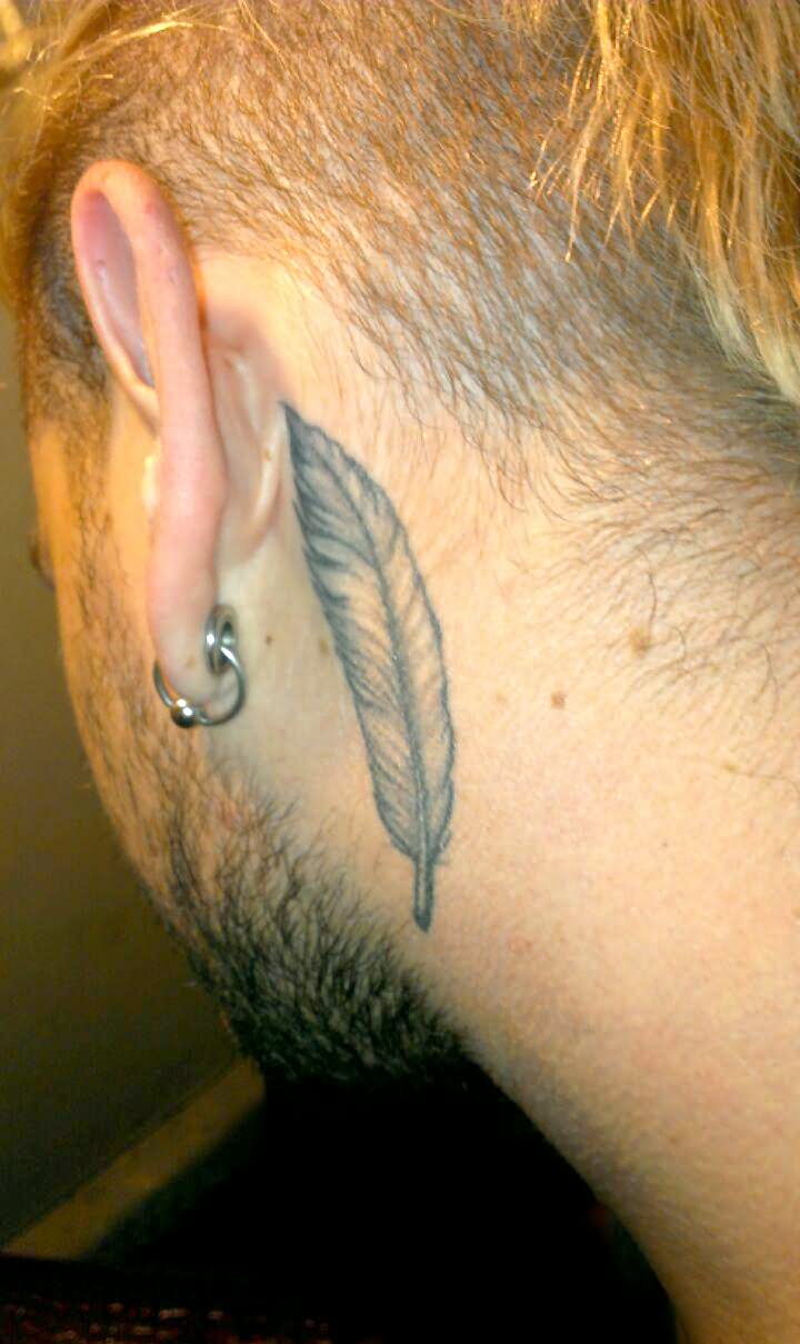 Grey Ink Feather Tattoo On Man Left Behind The Ear