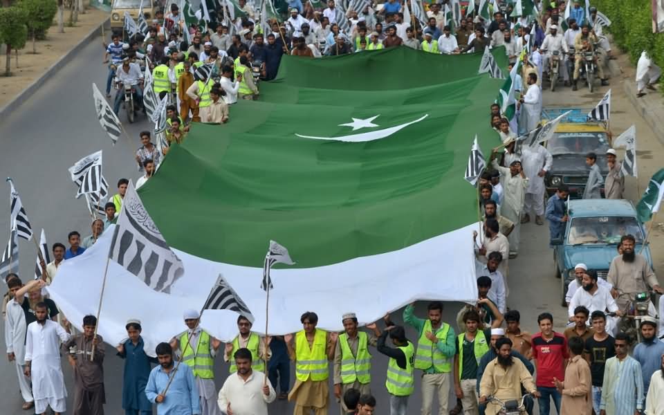 Pakistani People Walking With Big Pakistan Flag Celebrating Independence Day Of Pakistan