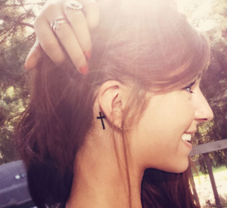 Simple Black Cross Tattoo On Girl Right Behind The Ear