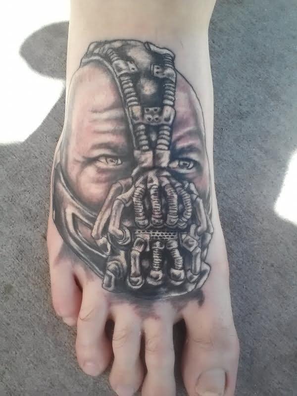 Black And Grey Bane Face Tattoo On Right Foot