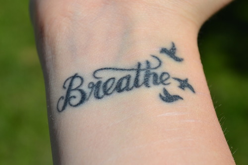 Black Flying Birds With Breathe Lettering Tattoo On Wrist By Olivia Goodwin