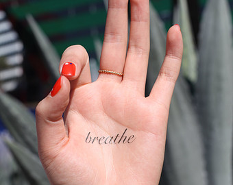 Breathe Lettering Tattoo On Girl Hand Palm