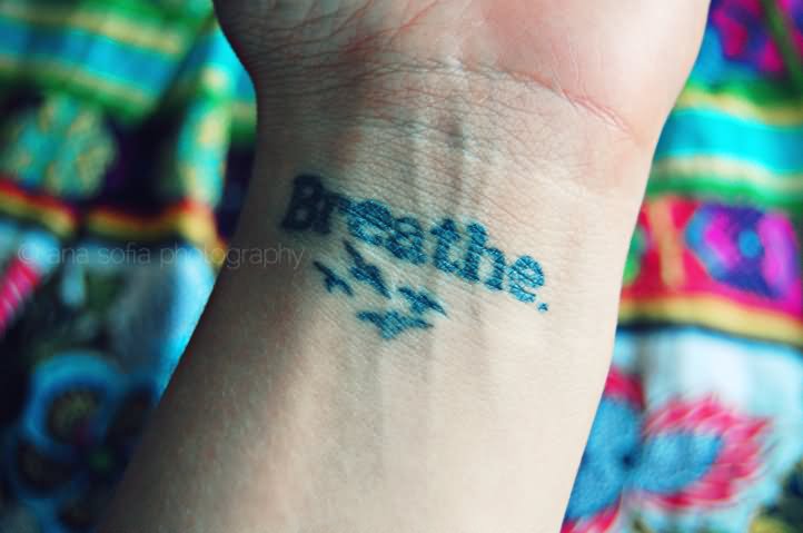 Breathe Lettering With Flying Birds Tattoo On Left Wrist
