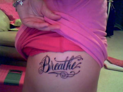 Classic Breathe Lettering Tattoo On Girl Left Side Rib