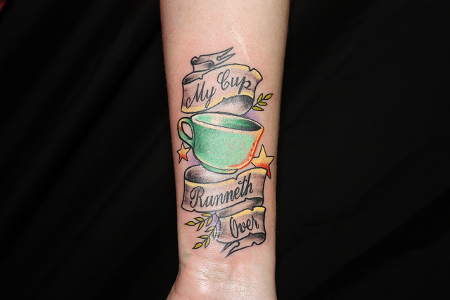 Grey Ink Banner And Simple Teacup Tattoo On Forearm