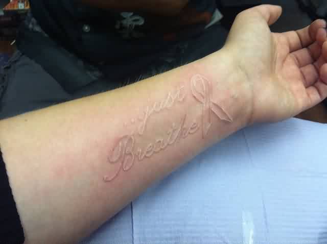White Ink Just Breathe Lettering With Cancer Ribbon Tattoo On Left Wrist