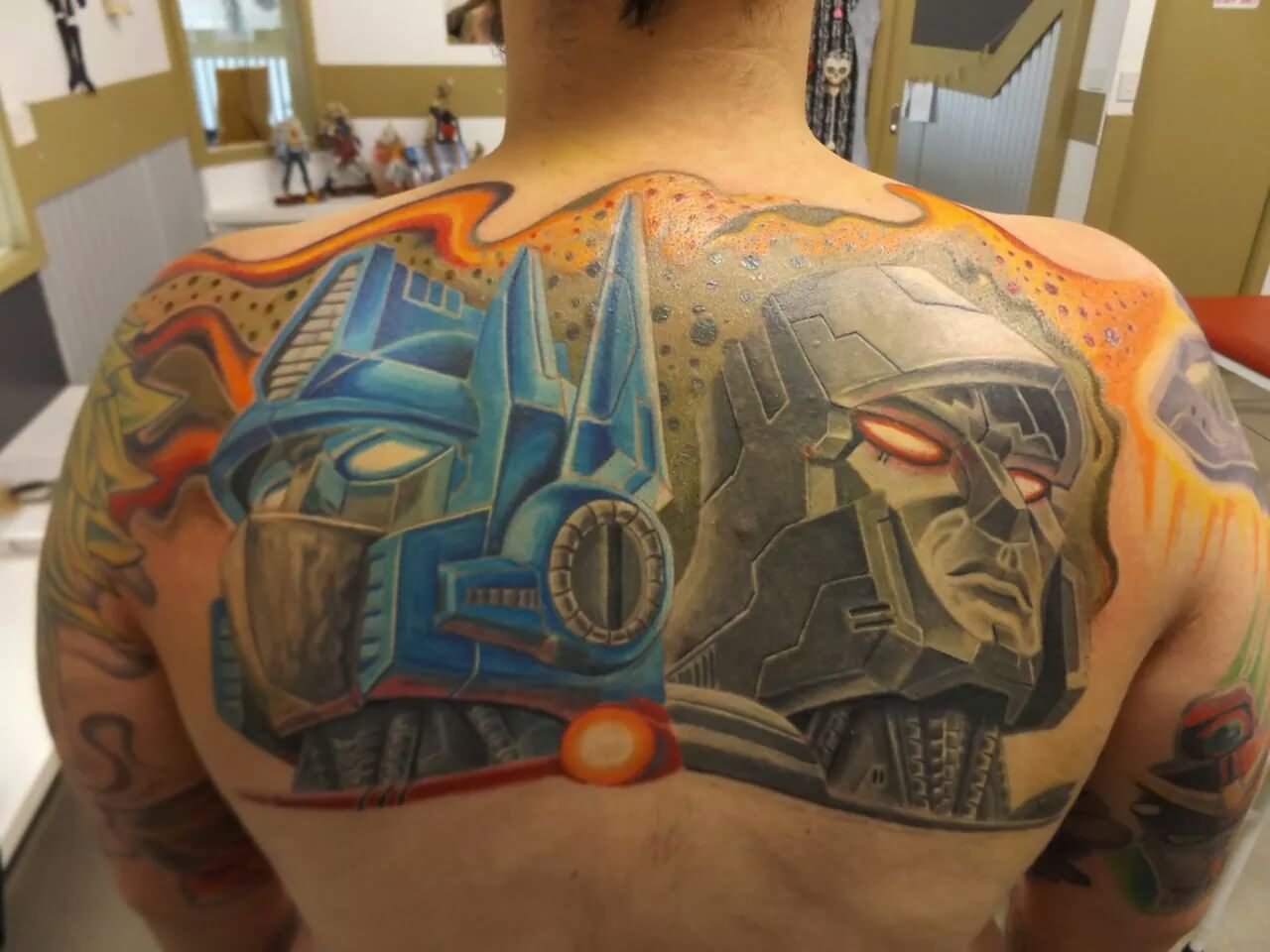 Attractive Two Transformers Tattoo On Man Upper Back