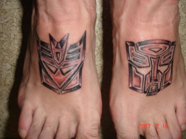 Black Ink Transformer Logo Tattoo On Feet