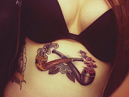 Traditional Two Crossing Pipe With Flower Tattoo On Girl Under Breast