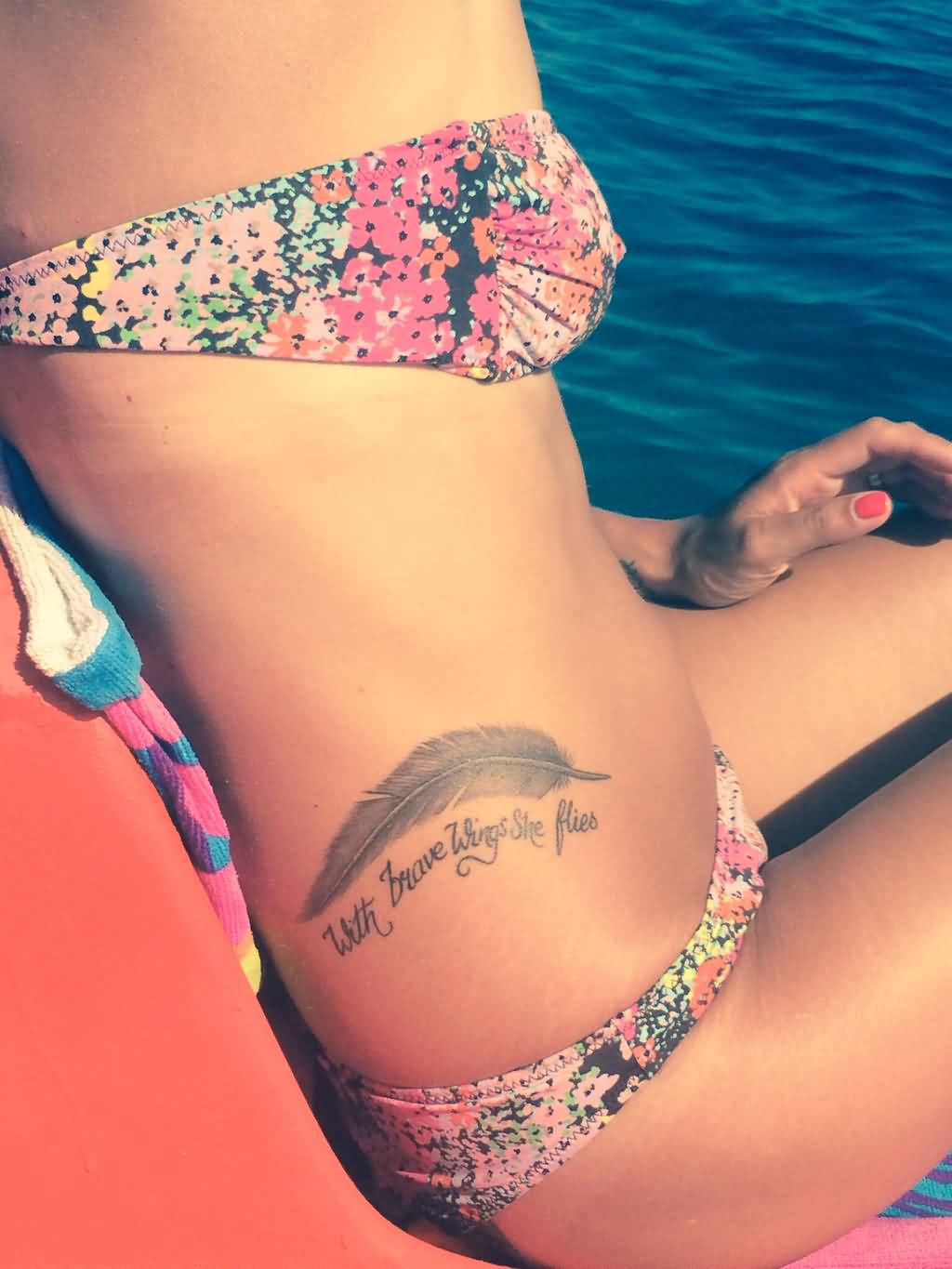 With Brave Wings She Flies - Grey Ink Feather Tattoo On Girl Right Hip