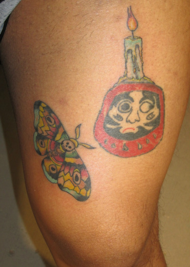 Candle On Daruma Doll With Butterfly Tattoo Design For Thigh