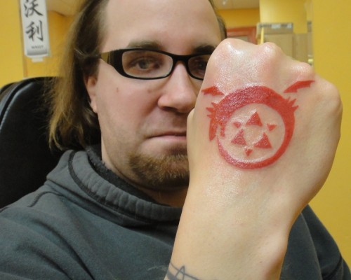 Red Ink Ouroboros Tattoo On Right Hand