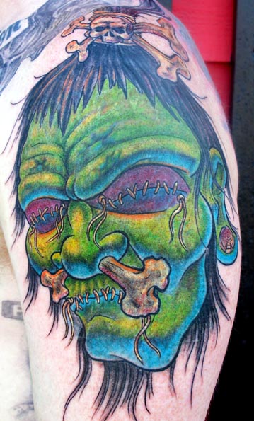 Green Ink Shrunken Head Tattoo On Left Shoulder