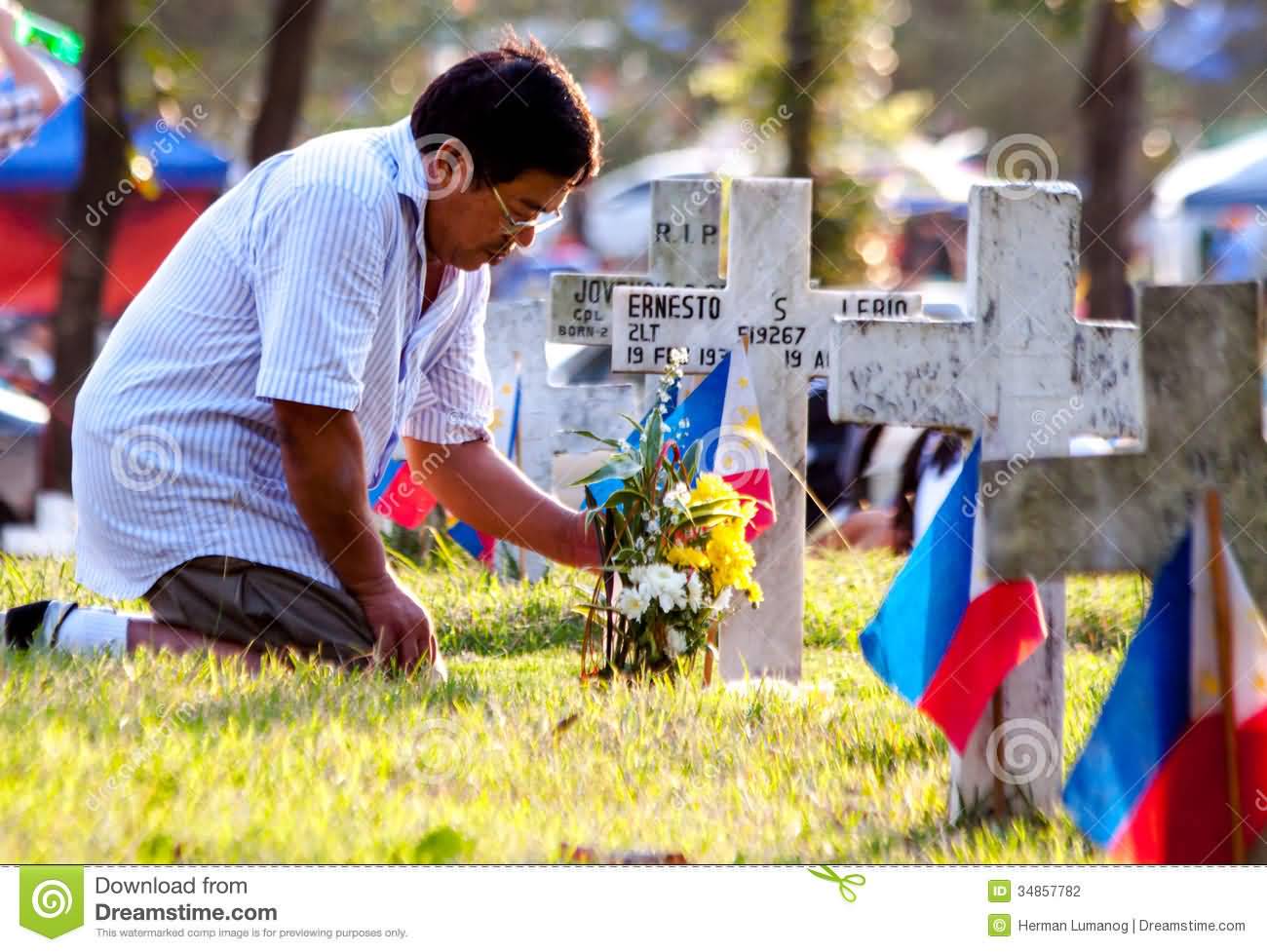 A Man Offering Flowers At Grave During All Saints Day