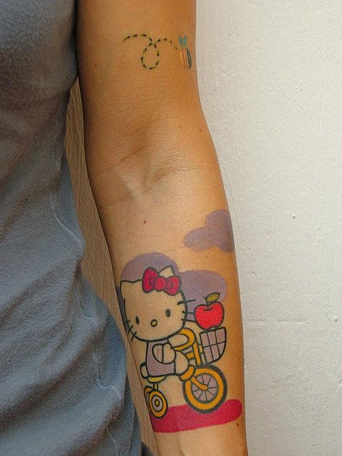 Hello Kitty On Bicycle Tattoo On Left Forearm