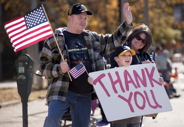 Man With His Family Waving Hand To Veterans Day Parade And With Thank You Banner