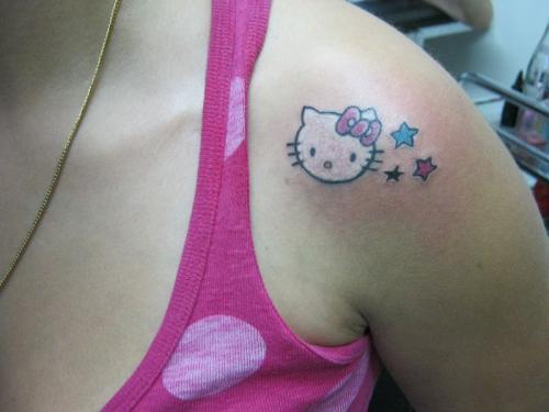 Small Colored Stars And Hello Kitty Tattoo On Left Shoulder