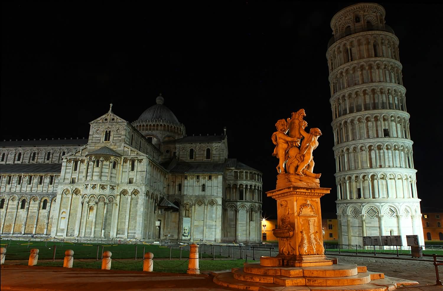 Statues Of Three Angels And Leaning Tower Of Pisa Illuminated At Night