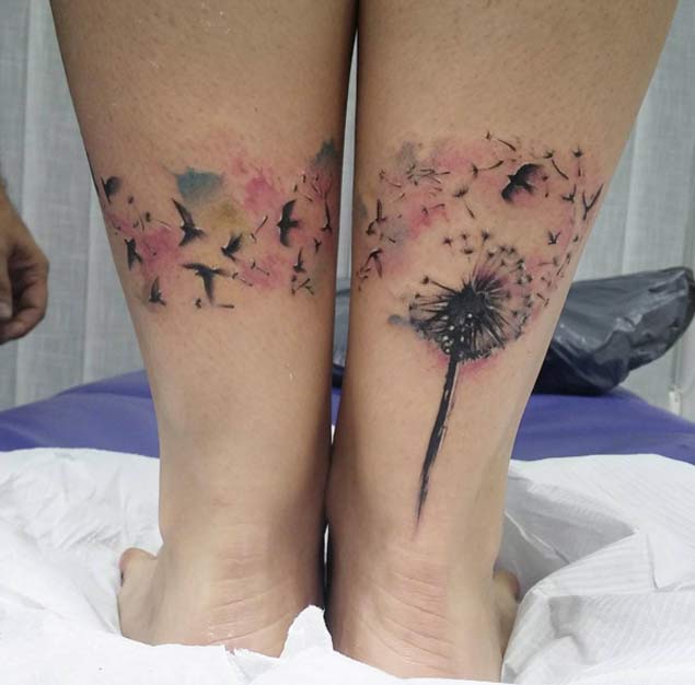 Birds Flying From Dandelion In Watercolor Tattoo On Back Legs by Carles Bonafe