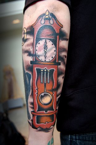 Color Ink Grandfather Clock Tattoo On Man Left Arm