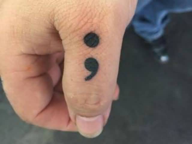 Semicolon Tattoo On Left Thumb