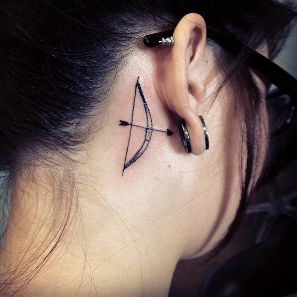 Behind Ear Bow And Arrow Black Color Tattoo For Girl