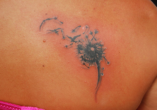 Birds Flying From Dandelion In Dark Black Ink Tattoo On Upper Back